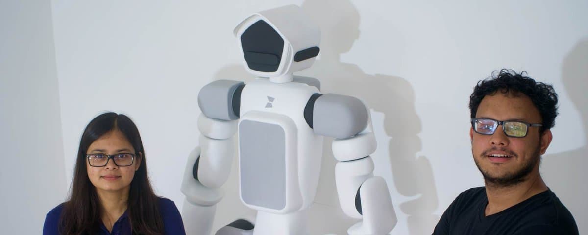 CoPAEI 0.1, a white humanoid, standing between two members of the team